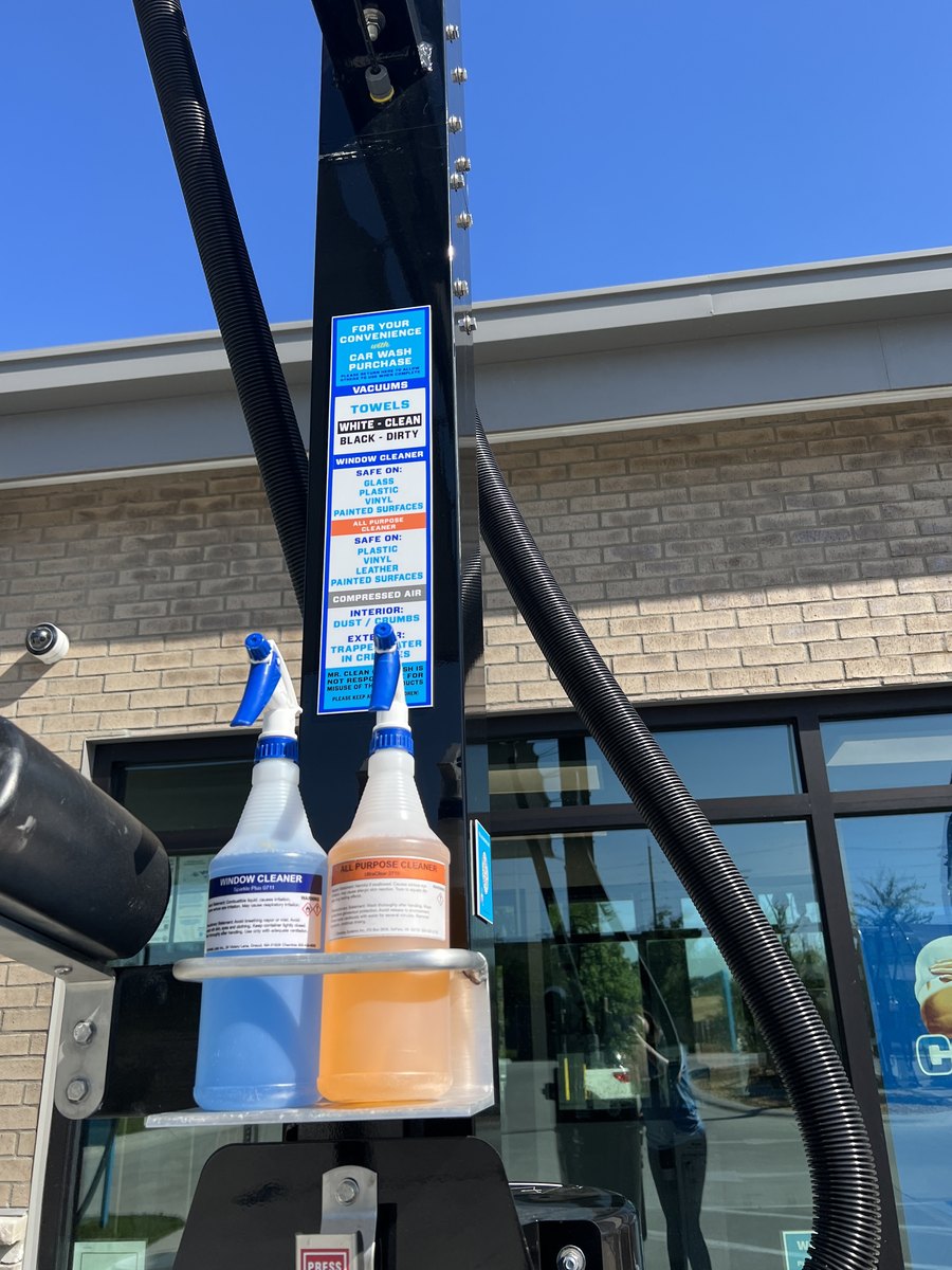 Sign at a Mr. Clean vacuum bay listing what comes free with a car wash — vacuums, towels, window cleaner, all-purpose cleaner and compressed air — with the cleaner bottles below it