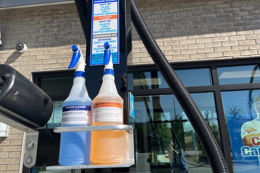 Window cleaner and all-purpose cleaner bottles at a Mr. Clean vacuum bay, free to use with any wash