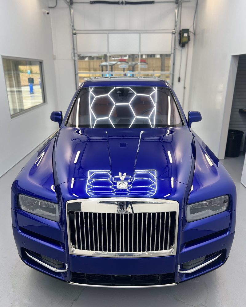 Bay lights mirrored in the hood of a blue Rolls-Royce Cullinan after coating