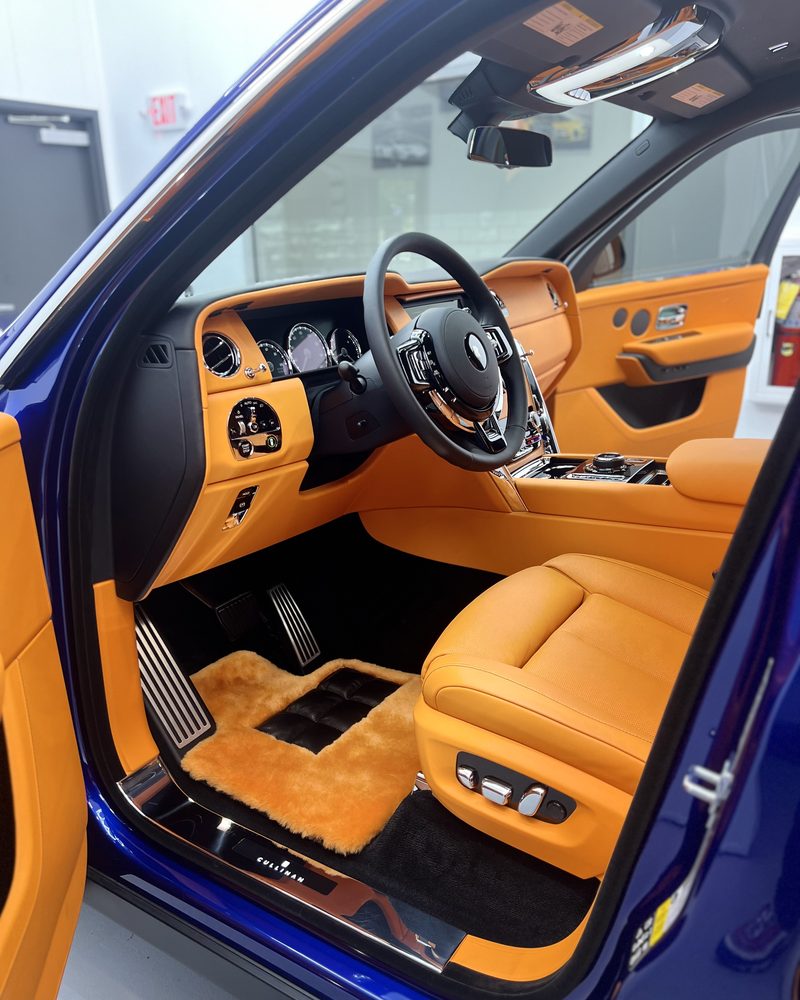 The tan leather interior of a Rolls-Royce Cullinan, door open against its blue paint