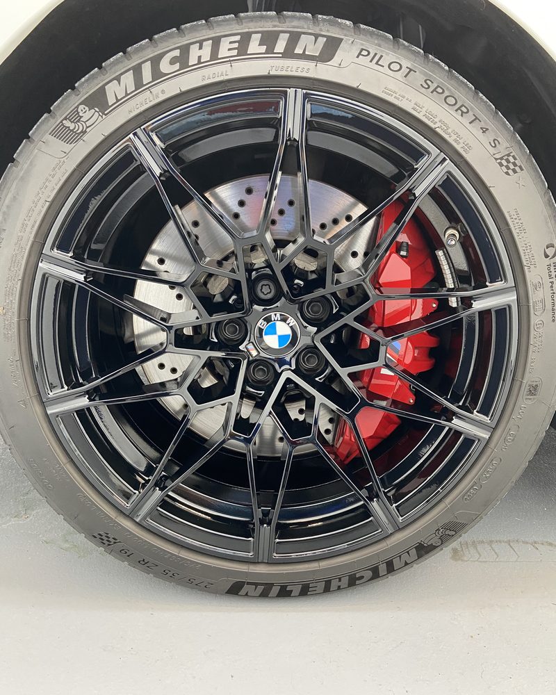 A coated wheel and red brake caliper, close up