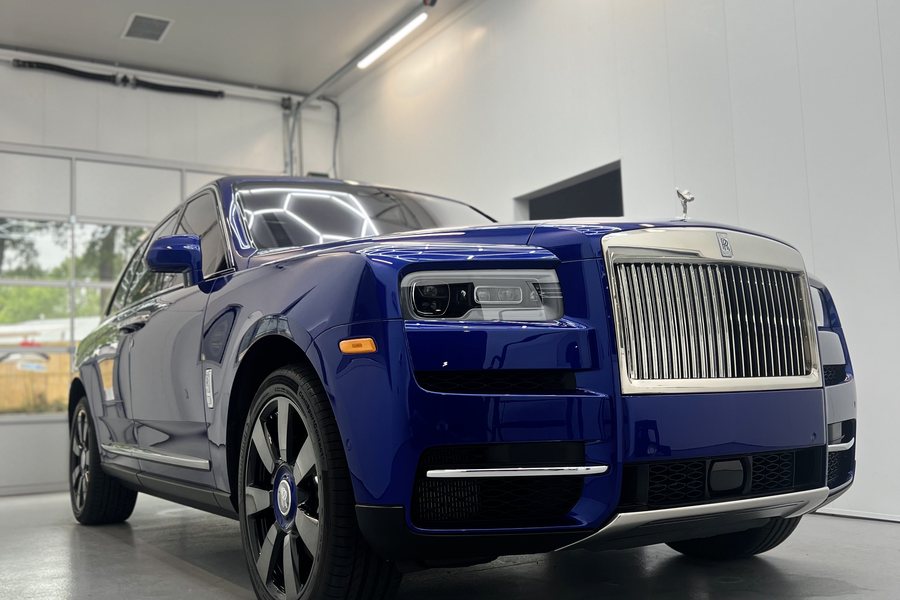 A ceramic-coated Rolls-Royce Cullinan in the detailing bay, its blue paint reflecting the overhead lights