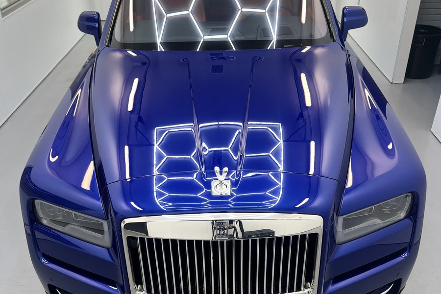 Overhead lights mirrored in the deep blue paint of a ceramic-coated Rolls-Royce Cullinan