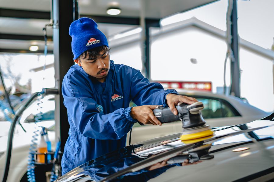 A Mr. Clean technician machine-polishing a car hood