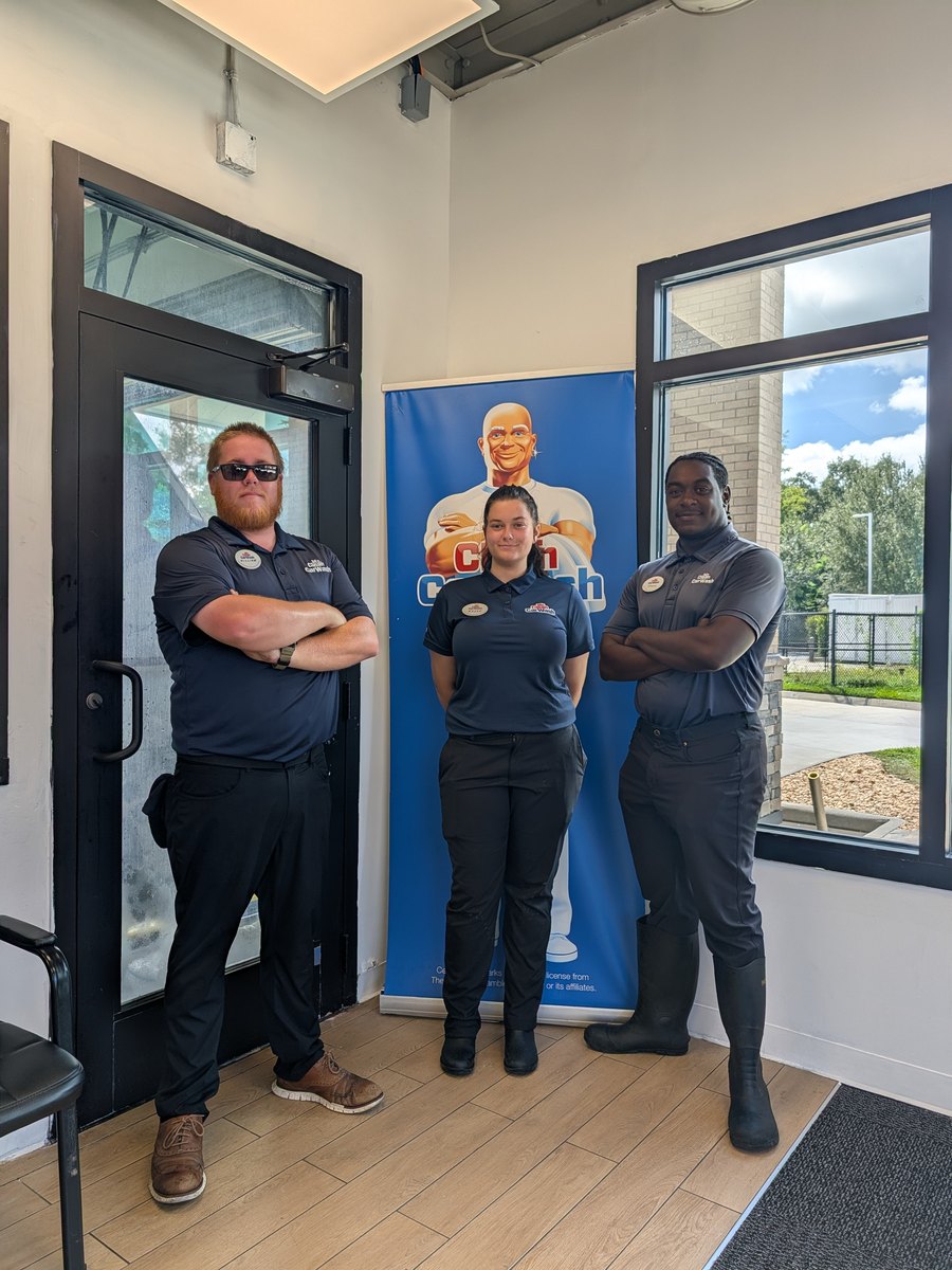 Three Mr. Clean Car Wash team members in uniform, arms crossed, in the lobby at Oxford